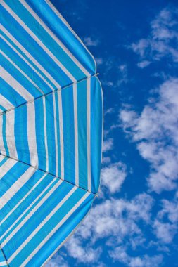 Menorca adasında bulutlar ve plaj şemsiyesiyle mavi gökyüzü arka planı