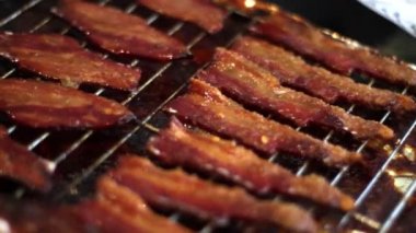 Pastırma rashers bir broiler altında yemek, yakın çekim. El ile yakın çekim fotoğraf makinesi düzenlenen.