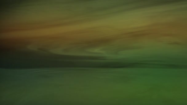 Green, yellow and orange tinted fog drifts across the screen, resembling planetary gas clouds.  Recorded against black and intended as a motion graphics background or for compositing.  Looping clip. 4K Royalty Free Stock Video