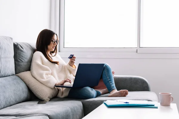 Evden online alışveriş yapmak için kredi kartı kullanan bir kadın.