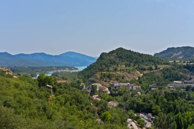 Ainsa köyü yeşil vadiye kurulmuş, turkuaz Mediano rezervuarı ve temiz bir gökyüzünün altındaki dağlarla çevrili.