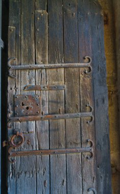 Yıpranmış eski ahşap kapı işlenmiş demir menteşeler, paslı bir kilit plakası ve Banyoles 'deki eski bir binanın yüzük sapı ile detaylandırılmış.