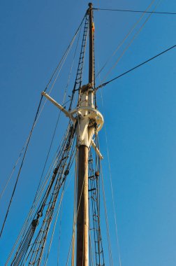 Barcelona 'da açık mavi bir gökyüzüne karşı geleneksel yelken gemisinde uzun tahta direk ve karmaşık halat donanımı.