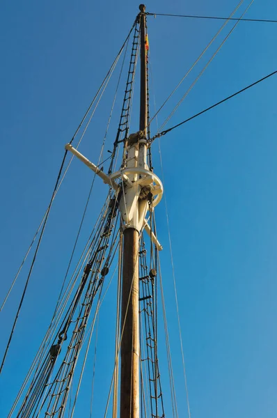 Barcelona 'da açık mavi bir gökyüzüne karşı geleneksel yelken gemisinde uzun tahta direk ve karmaşık halat donanımı.