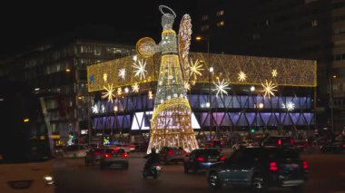 İspanya, Madrid, 127 2025, İspanya 'nın Madrid şehrinde aydınlık bir Noel meleği dekoru etrafında gece trafiği.