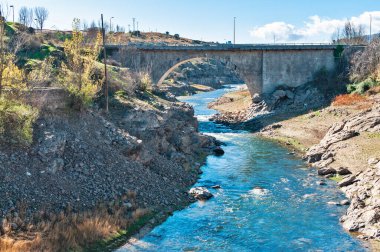 Lozoya Nehri Buitrago de Lozoya 'daki antik bir taş köprünün altından akıyor, düşük su seviyeleri ve kuru bankalar sergileniyor.