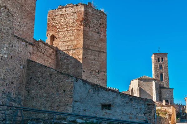 Historic walls and ancient church tower under clear blue sky. Exploring architecture and heritage in a fortified Spanish town