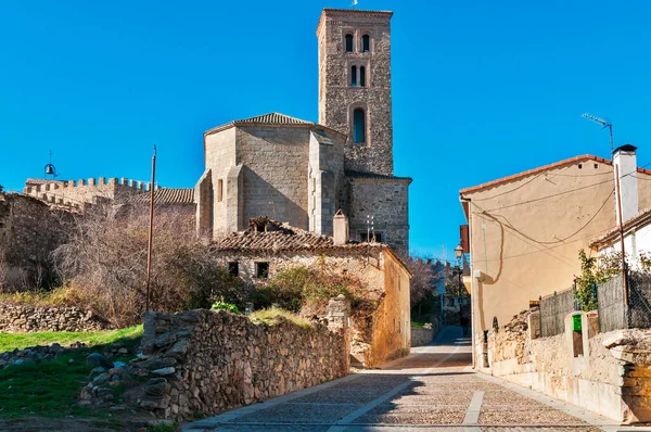 Historic Buitrago del Lozoya town street with an old church and its bell tower under a clear blue sky