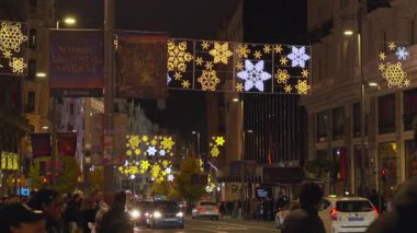 Madrid, İspanya, 12102025, Madrid 'de işlek bir caddede Noel ışıkları altında yürüyen yayalar ve arabalar.