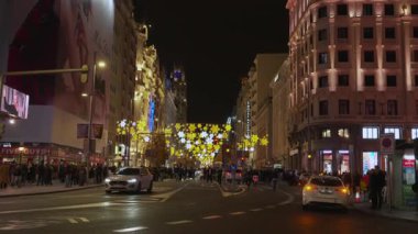 Madrid, İspanya, Noel, 12-14-2025: İnsanlar ve arabalar Madrid 'de Gran Via caddesinde gece boyunca Noel süslemeleriyle geziyorlar
