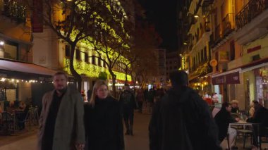 Madrid, İspanya, Noel, 12-14-2025: Geceleri Madrid 'de kalabalık bir yaya caddesinde insanlar yürüyüş ve akşam yemeği yiyor