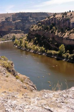 Üzerinde bir grup kano olan bir nehir. Su kahverengi ve gökyüzü mavi.