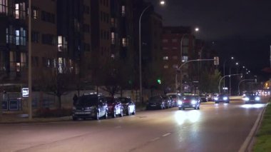 Madrid, İspanya, 02-13-2026: Gece yarısı yol kenarında arabaların park ettiği bir cadde. Sokaklar aydınlık ve arabalar aydınlık.