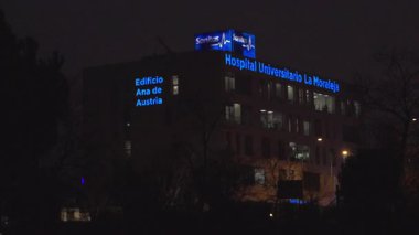 Madrid, İspanya, 02-13-2026: Üzerinde mavi ışıklar olan büyük bir bina. Bina bir hastane. Işıklar gece açık.