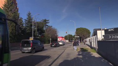 Madrid, İspanya, 02 23 2025, güneşli bir günde Madrid, İspanya 'da bir banliyö otobüs durağında otobüs bekleyen banliyö sakinleri.