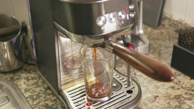 Taze sıcak espresso hazırlama süreci. Modern profesyonel kahve makinesi temiz cam bir fincana kahve döküyor.