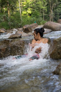 Sabahları yağmur ormanlarının soğuğunun tadını çıkaran bir erkek gezgin. Şelale havuzunda duş alan bir adam..