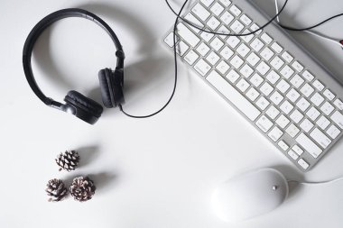 Akıllı telefon, kulaklık, bilgisayar klavyesi ve fareli beyaz ofis masası. Kopyalama alanı olan üst görünüm. Düz konum.