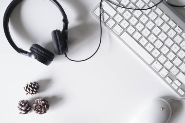 Akıllı telefon, kulaklık, bilgisayar klavyesi ve fareli beyaz ofis masası. Kopyalama alanı olan üst görünüm. Düz konum.