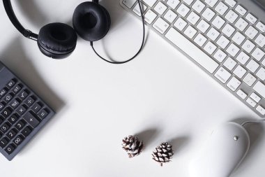 Akıllı telefonu, kulaklığı, bilgisayar klavyesi ve faresi olan beyaz ofis masası. Kopya alanı olan üst görünüm. Düz konum.