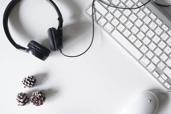 Akıllı telefon, kulaklık, bilgisayar klavyesi ve fareli beyaz ofis masası. Kopyalama alanı olan üst görünüm. Düz konum.