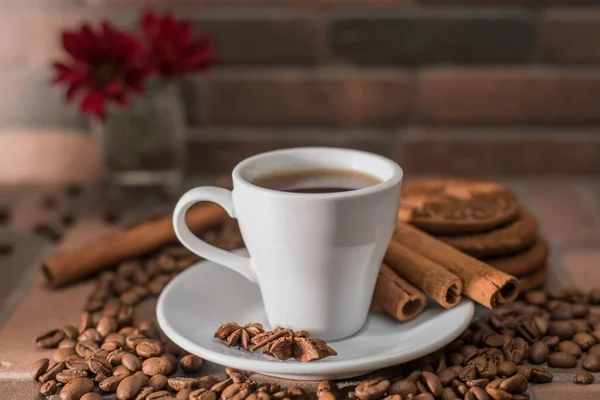 Bir fincan kahve, kahve çekirdekleri, kurabiyeler ve koyu arkaplanda bir mum.