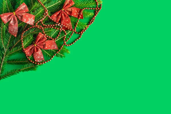 绿色背景的圣诞装饰品 在云杉枝上装饰红色蝴蝶结的节日装饰 复制空间 — 图库照片