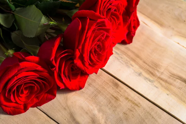 Букет красных роз, лежащих на деревянном столе — стоковое фото