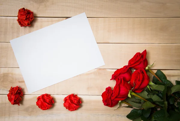 Blank sheet of paper on the table beside him a bouquet of red ro Royalty Free Stock Images