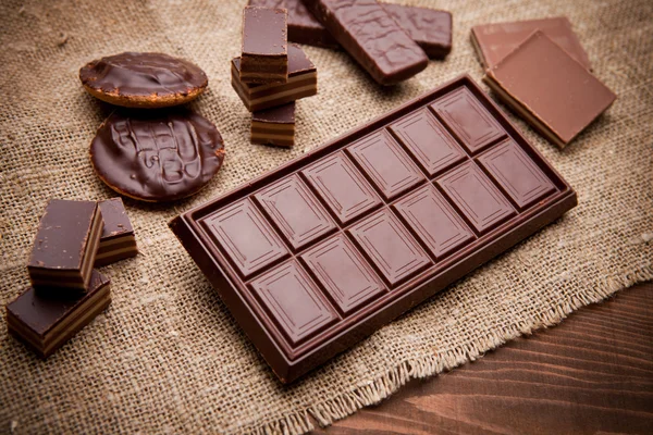 Piezas de chocolate sobre mesa de madera — Foto de Stock