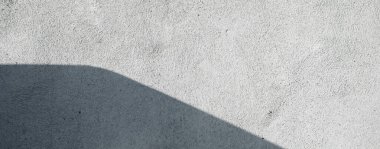 Açık gri duvarlı arka plan çizikler ve çatlaklarla kaplı ve köşesinde bir gölge var. Yüksek çözünürlüklü pis duvar dokusu. Panoramik pankart