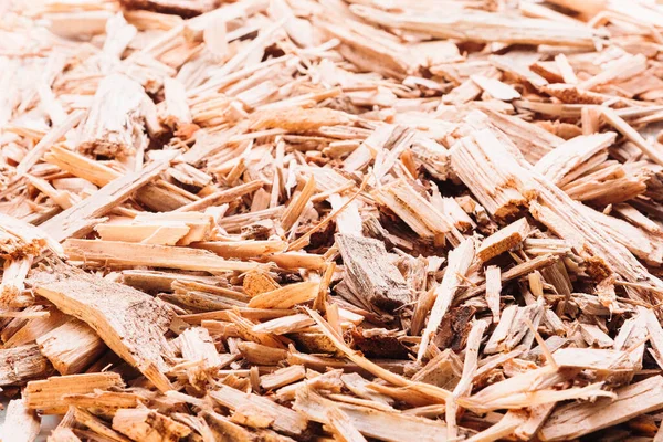 Small pile of wood chips close up background. Waste from the woodworking industry, fuel and raw materials for heating solid fuel industrial boilers on wood chips