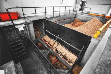 Katı yakıtlı endüstriyel kazanları vida çipli besleme sistemiyle ısıtmak için odun çipi deposu. Ahşap endüstrisinin atıklarıyla dolu beton bir tank..