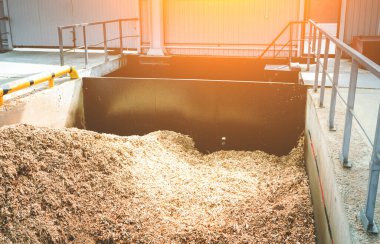 Katı yakıt endüstriyel kazan dairesinde odun parçaları depolamak için bir sığınak. Ahşap endüstrisinin atıklarıyla dolu beton bir tank. Güneş patlaması