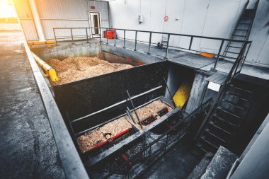Katı yakıtlı endüstriyel kazanları vida çipli besleme sistemiyle ısıtmak için odun çipi deposu. Ahşap endüstrisinin atıklarıyla dolu beton bir tank. Güneş parlaması