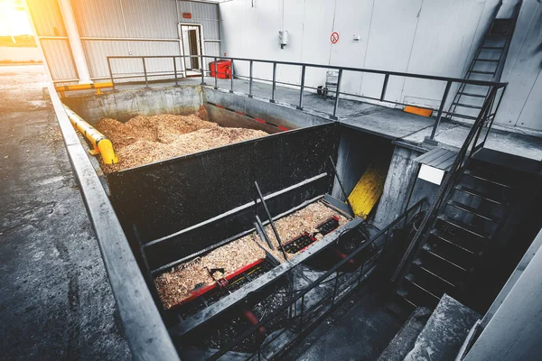 Katı yakıtlı endüstriyel kazanları vida çipli besleme sistemiyle ısıtmak için odun çipi deposu. Ahşap endüstrisinin atıklarıyla dolu beton bir tank. Güneş parlaması