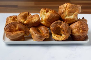Yorkshire pudingleri beyaz bir tepsiye istiflenmiş olarak yan taraftan izleniyor.