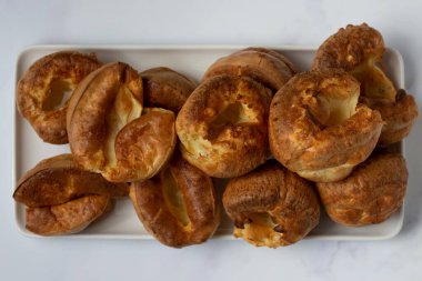 Yorkshire pudinglerinin beyaz tepside üst üste yığılmış görüntüsü.