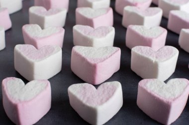 Aşk kalp lokumları farklı renklerde sıraya dizilmiş ve yandan izleniyor.