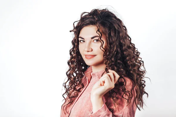 Beyaz arka planda kameraya poz veren kıvırcık saçlı güzel bir kadın..