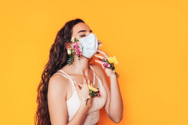 Salgın sırasında çiçeklerden yapılmış tıbbi maske takan genç bir kadın..
