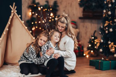 Çocuklar ve anneleri bir çadır ve Noel ağacına sarılıyorlar. Noel havası. Tatili tüm ailenle kutla..