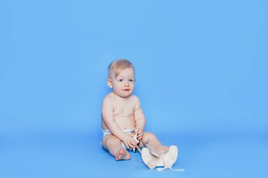 Küçük çocuk mavi bir arka planın önünde oturuyor. Çocuklara iyi bak. Çocuk evlat edinmek. Suni döllenme.