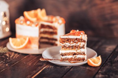 Beyaz bir tabakta çatalla dilimlenmiş kek. Her bayram için şeker. Tahta bir arka planda, çelenkler ve bir fenerle. Beyaz tabakta çocuk oyuncağı..