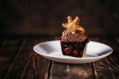 Tahta zemin üzerinde yıldız şeklinde kurabiyeler olan bir tabakta çikolatalı kekler. Noel havası. Her durum için şeker. Kek kesimi, meyve doldurma..