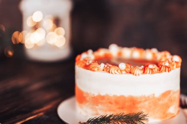 Beyaz bir tabakta çatallı kek. Her bayram için şeker. Tahta bir arka planda çelenkler ve bir fenerle.