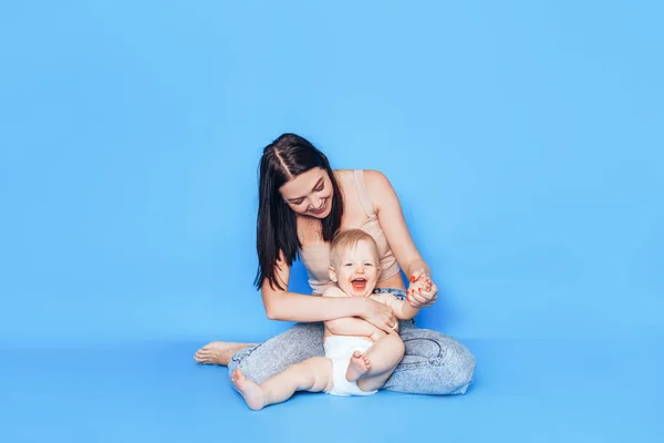 Genç Bir Anne Mavi Bir Arka Planda Küçük Oğluyla Oynar — Stok fotoğraf