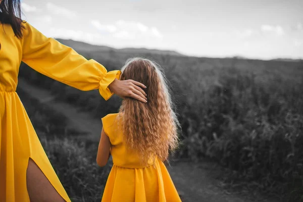 小さな子供とともに母で黄色照明ドレス上のグレー自然背景 — ストック写真