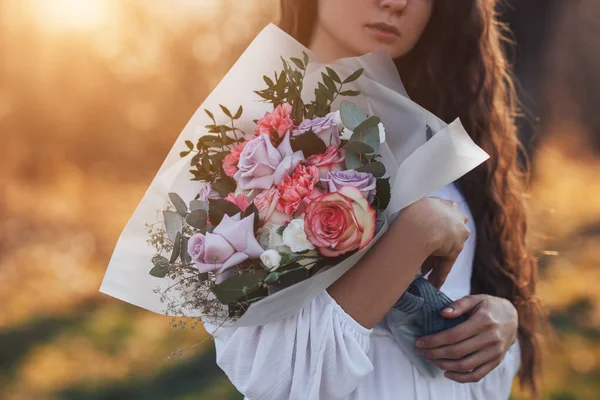 Mujer joven en vestido blanco sosteniendo un hermoso ramo de rosas —  Fotos de Stock