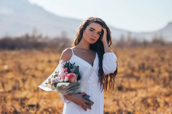 Mujer joven en vestido blanco sosteniendo un hermoso ramo de rosas —  Fotos de Stock